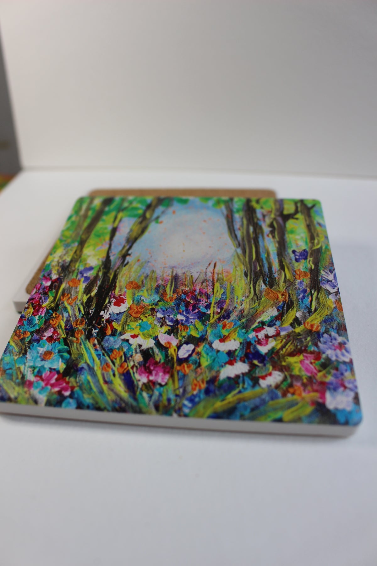 10x10cm square ceramic coaster featuring a colorful, hand-painted floral forest art print with a protective cork backing.