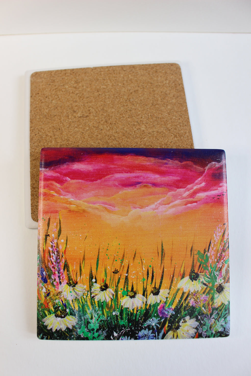10x10cm square ceramic coaster with a vibrant hand-painted floral meadow sunset print and protective cork backing.