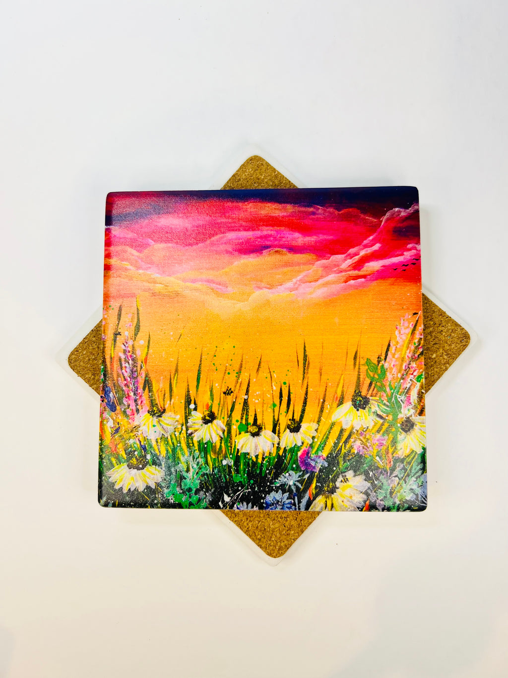 Square ceramic coaster showing a vibrant sunset sky over tall grass and flowers