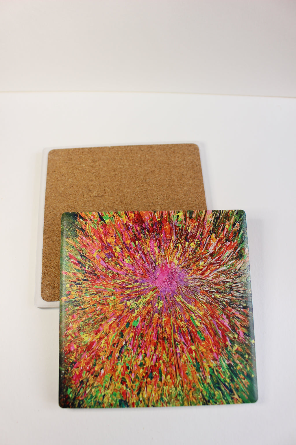 10x10cm square ceramic coaster featuring a vibrant, hand-painted abstract explosion design with a protective cork backing.