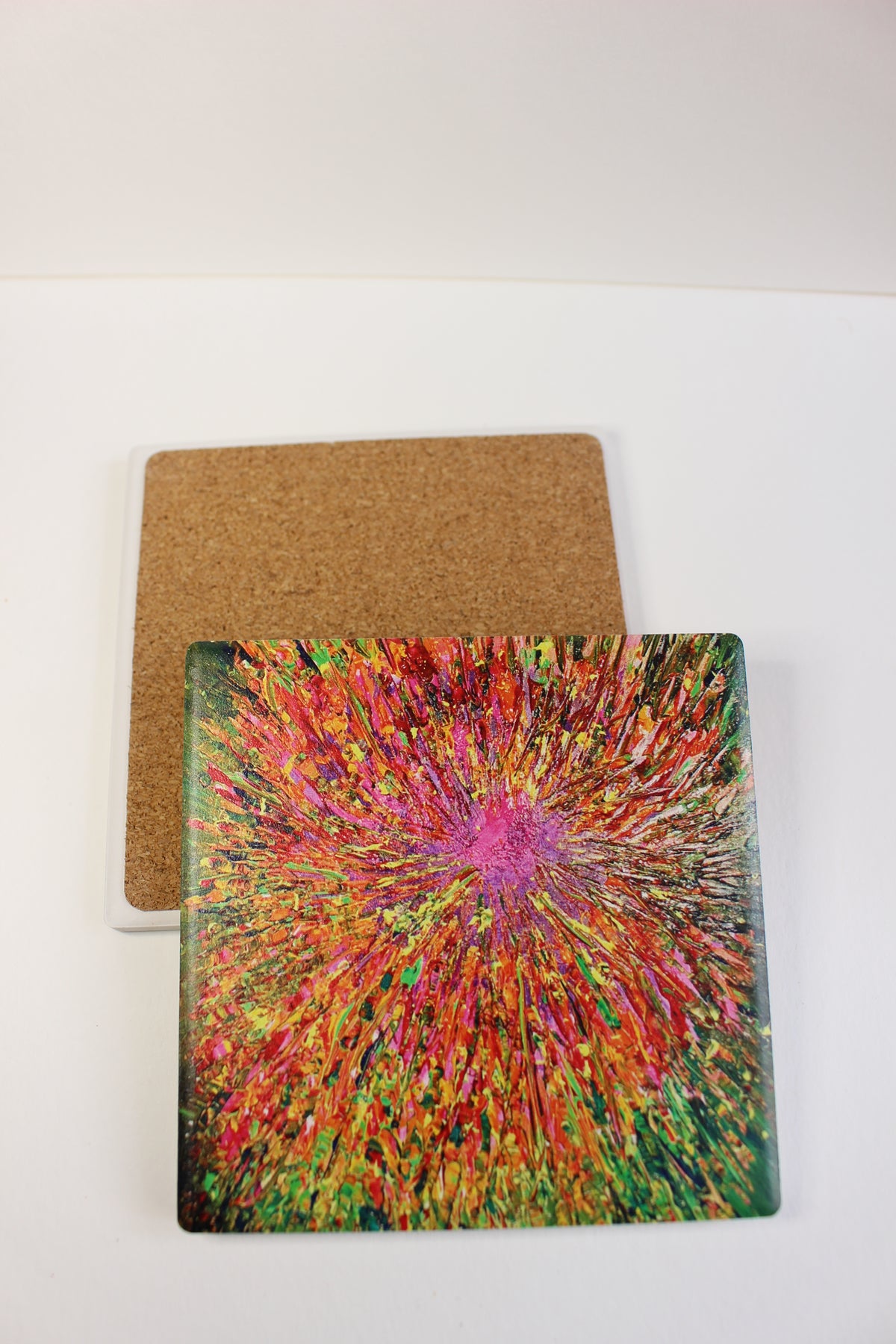 10x10cm square ceramic coaster featuring a vibrant, hand-painted abstract explosion design with a protective cork backing.