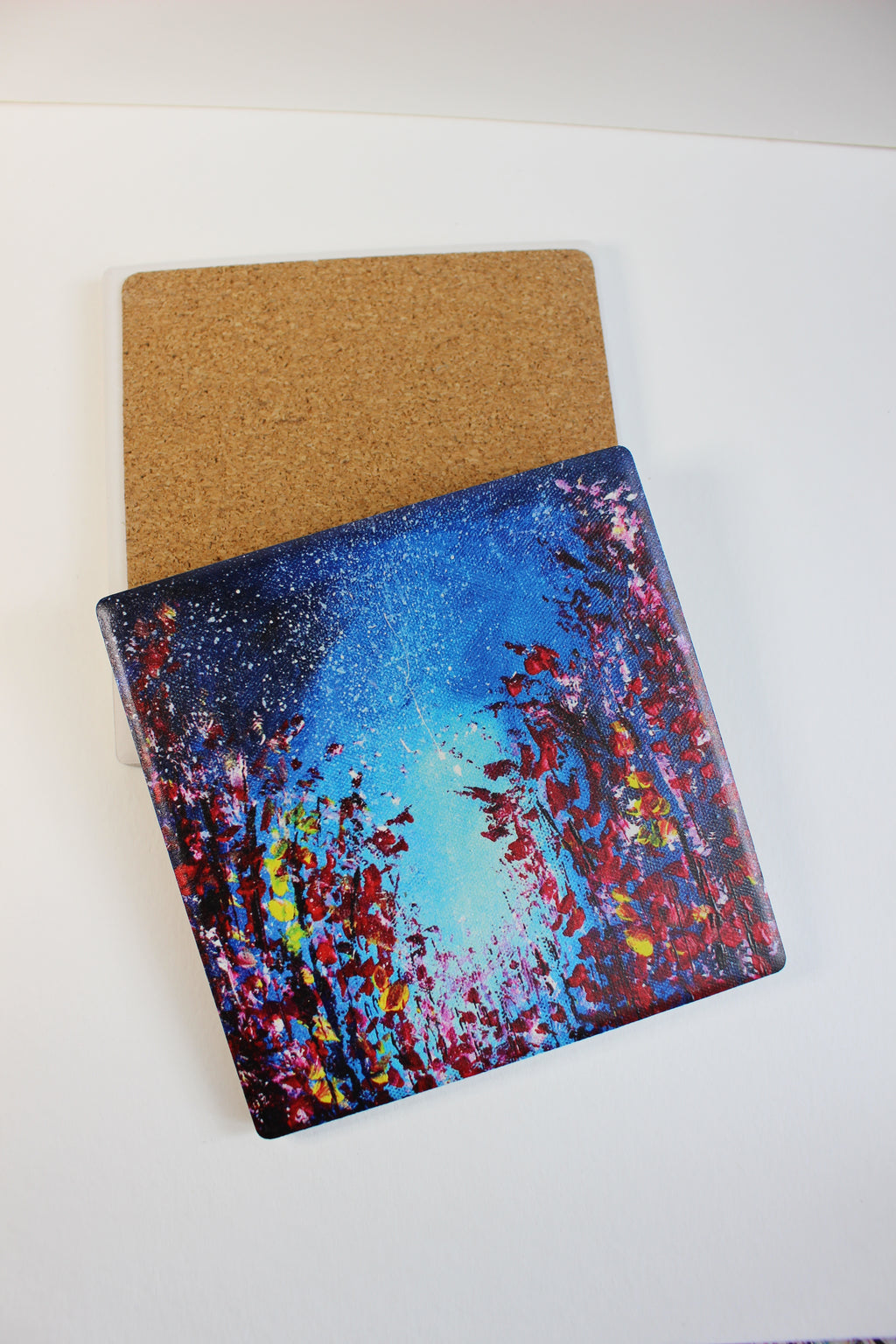 10x10cm square ceramic coaster featuring a vibrant hand-painted starry night art print with a protective cork backing.