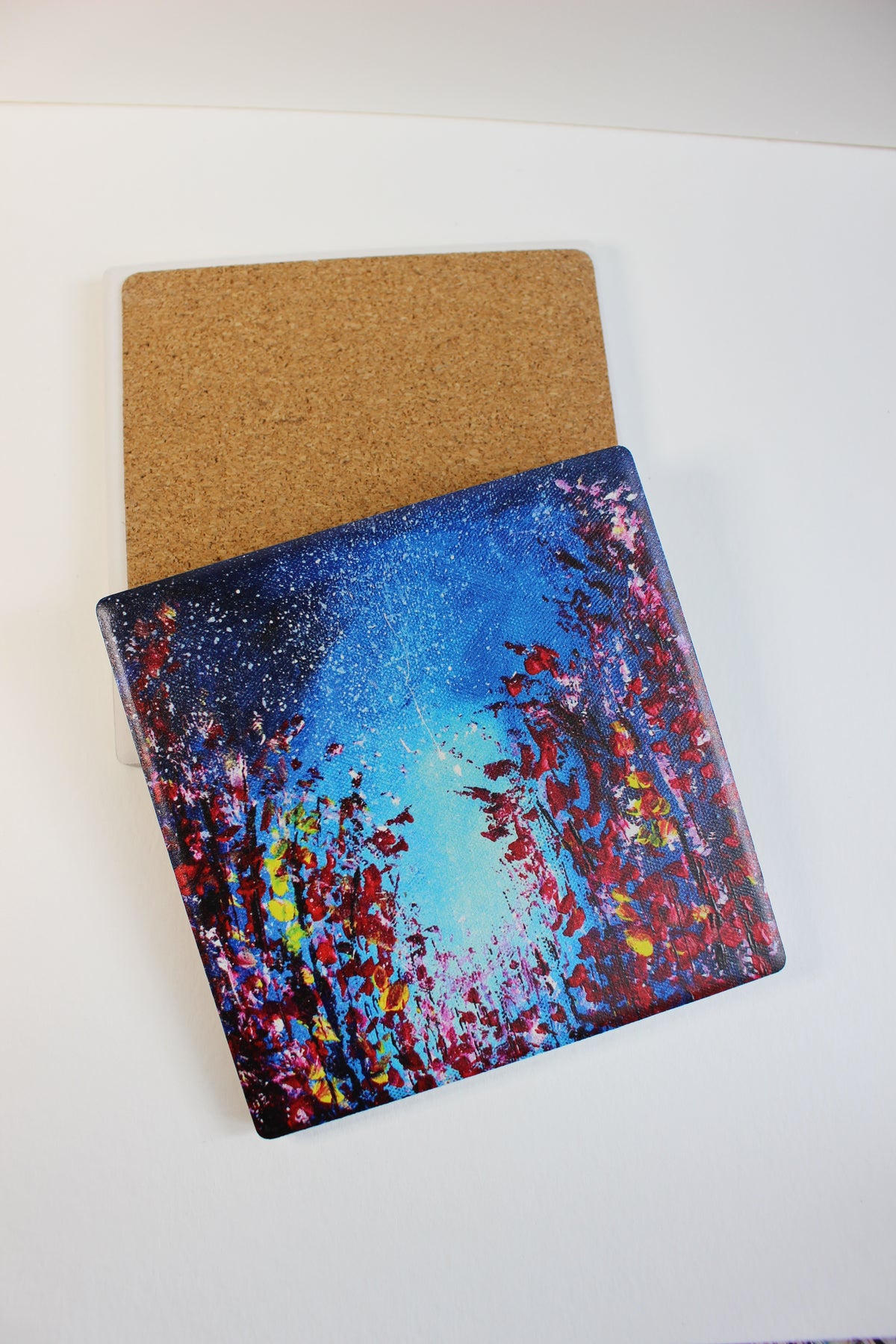 10x10cm square ceramic coaster featuring a vibrant hand-painted starry night art print with a protective cork backing.