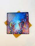 Square ceramic coaster with blue and multicolor starry art print; tan cork pads