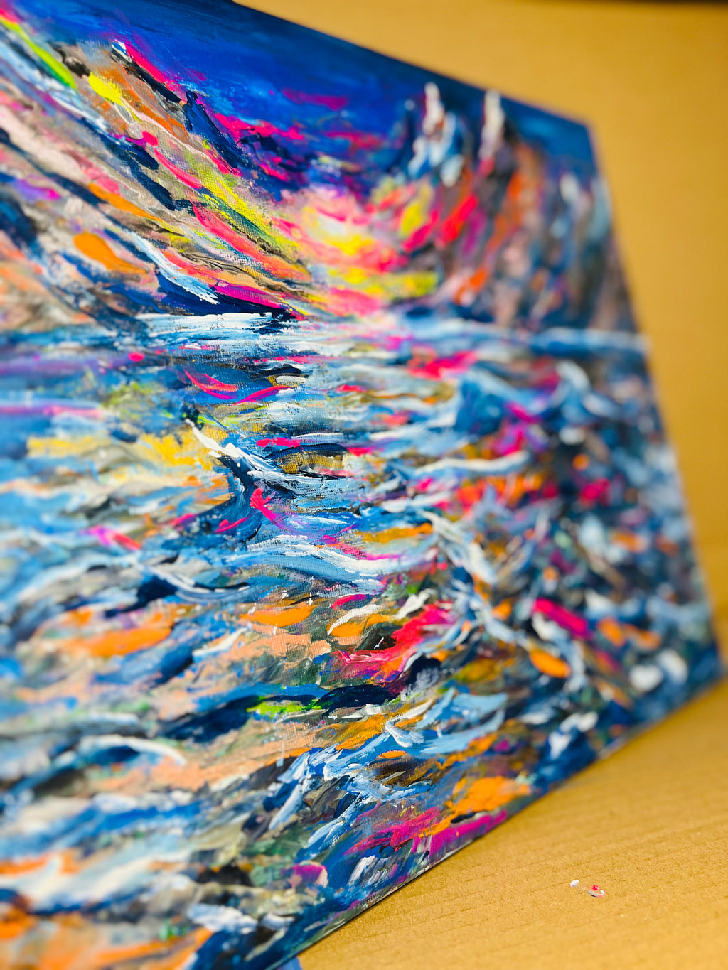 Abstract canvas painting angled view showing textured blue and multicolor paint strokes