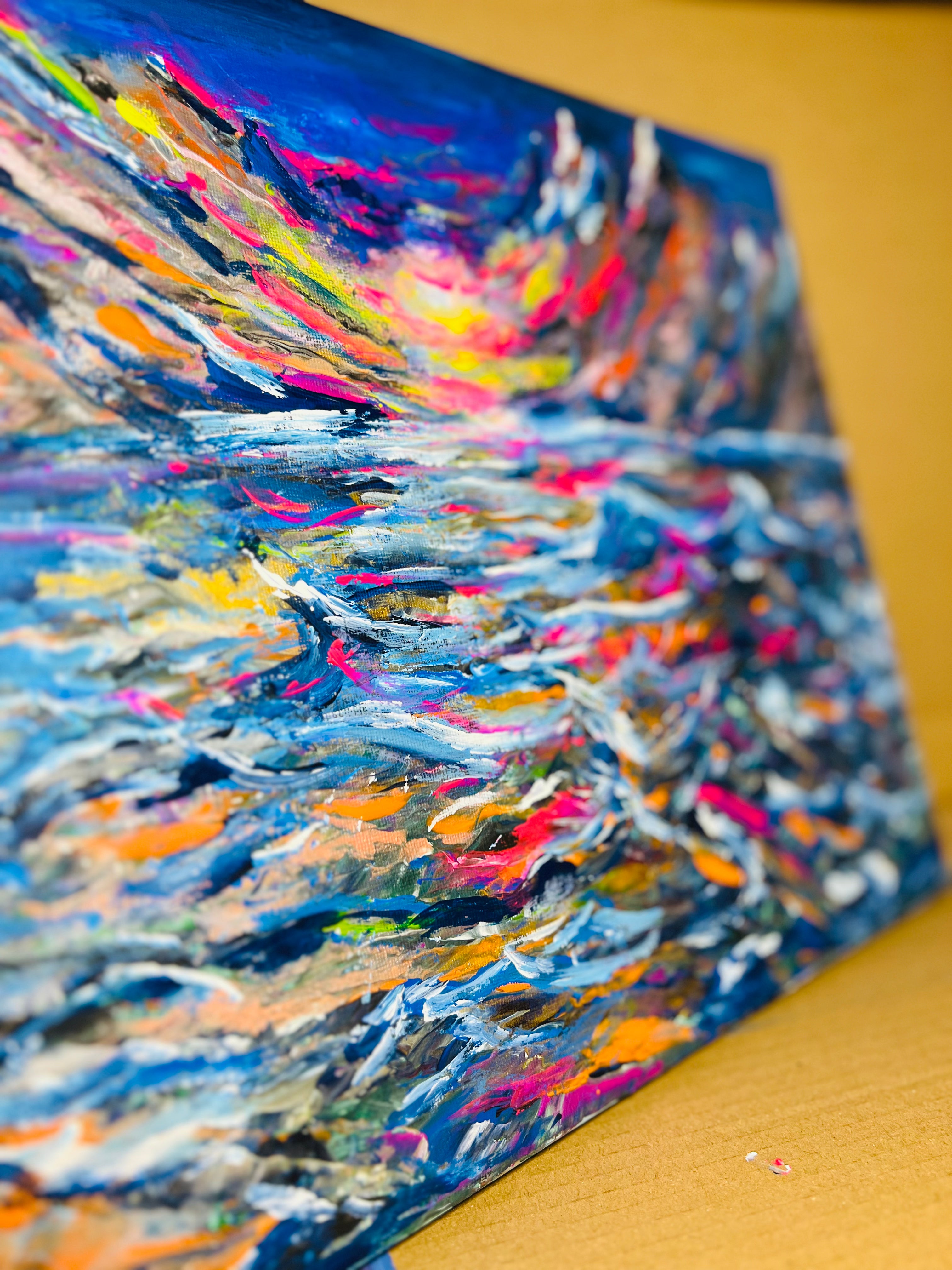 Abstract canvas painting angled view showing textured blue and multicolor paint strokes