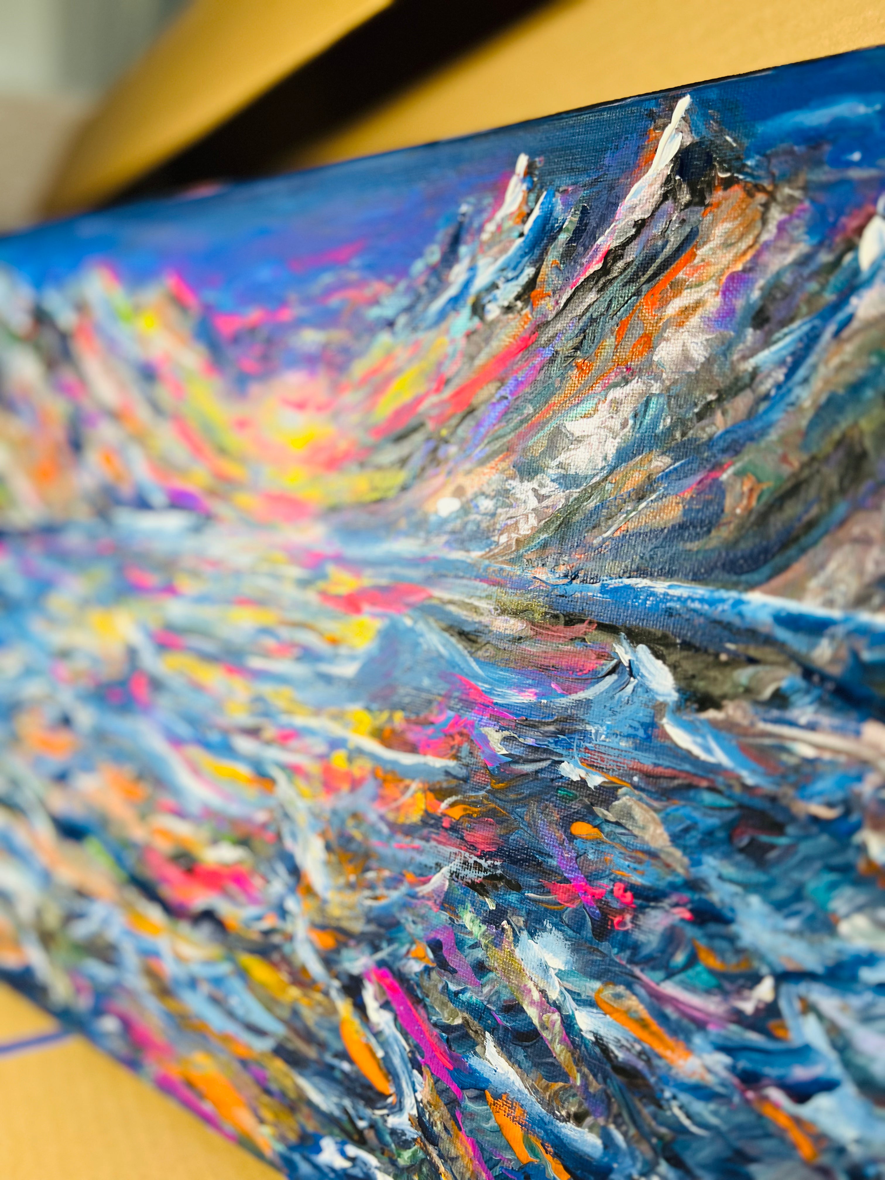 Abstract canvas painting with blue sky tones and white streaks over multicolor paint texture