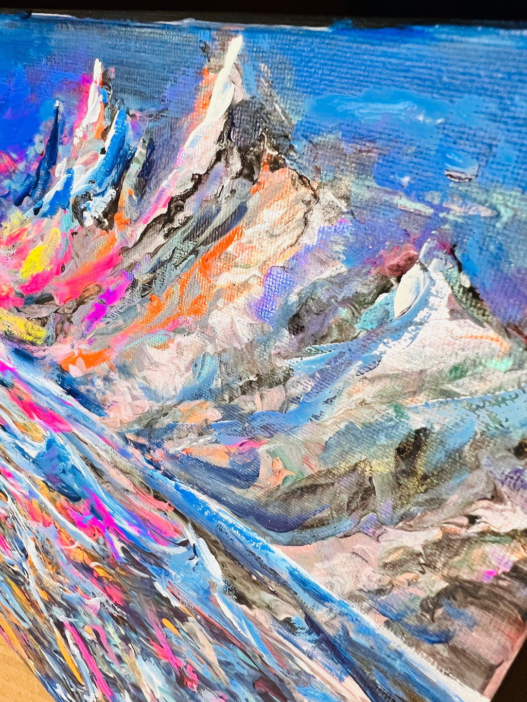 Abstract canvas painting showing layered blue waves with white highlights and colorful accents