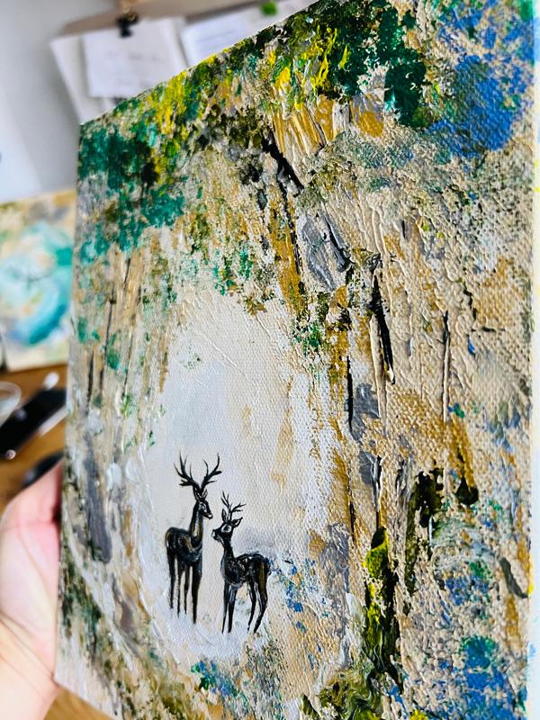 Canvas wall art held in hand, showing deer silhouettes and textured forest streaks